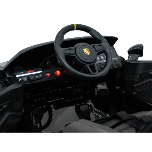 Kokpit z kierownicą, panelem audio i pedałem gazu – wnętrze czarnego Porsche Spyder RS 718 na akumulator dla dzieci.webp