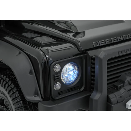 Świecący reflektor LED i napis DEFENDER na masce – zbliżenie czarnego Land Rovera Defender 110 SVX Concept na akumulator dla dzieci.webp