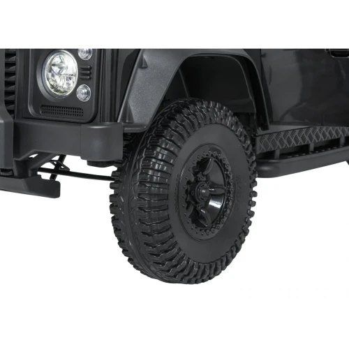 Koło z terenową oponą i czarną felgą – zbliżenie czarnego Land Rovera Defender 110 SVX Concept na akumulator dla dzieci.webp