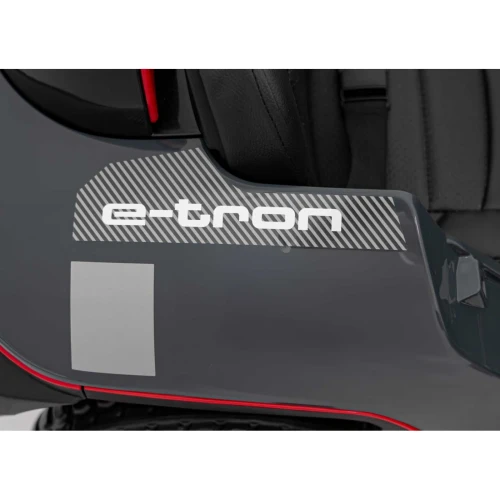 Napis e-tron i czerwona listwa na tylnym błotniku – zbliżenie karoserii szarego Audi RSQ e-tron na akumulator dla dzieci.webp