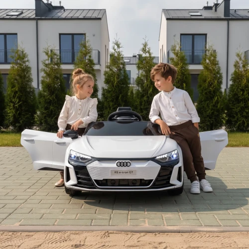 Białe Audi RS E-tron z dziewczynka i chłopcem - otwarte drzwi na osiedlu.webp