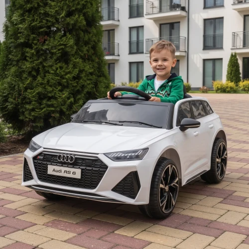 Białe Audi RS 6 z dzieckiem w środku przed blokiem mieszkalnym - merikids.webp