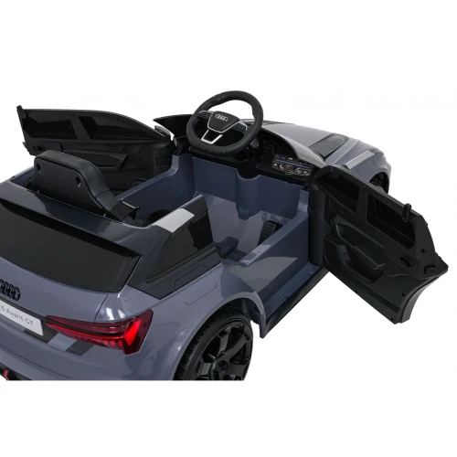 Kokpit z kierownicą Audi i panelem sterowania przy otwartych drzwiach – wnętrze szarego Audi RS6 Avant GT, auta elektrycznego na akumulator dla dzieci.webp