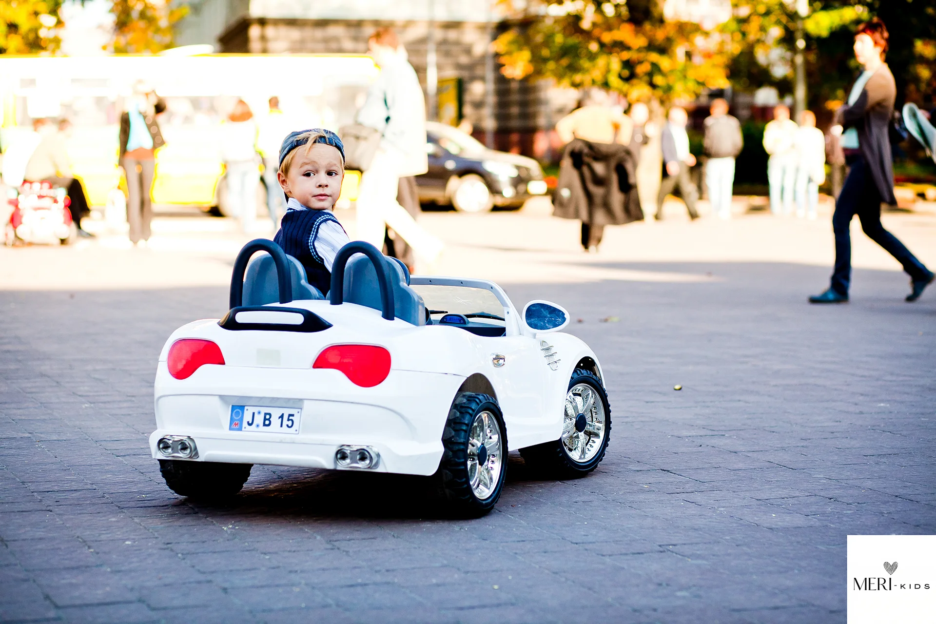 Dziecko jeżdżące czerwonym autkiem elektrycznym po ogrodzie - radosna zabawa na świeżym powietrzu